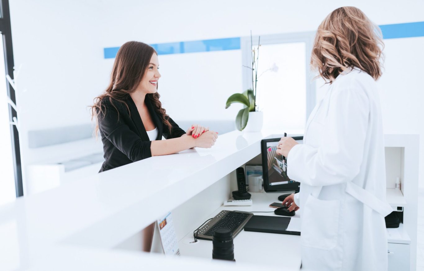 Patientin an der Rezeption einer modernen Zahnarztpraxis. Dank der digitalen Rezeption und dem KI-Anrufbeantworter von DokFee werden Anfrage